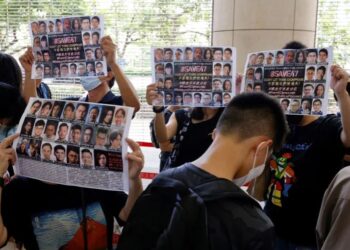 Supporters hold up placards among people queueing up at the West Kowloon Magistrates' Courts.