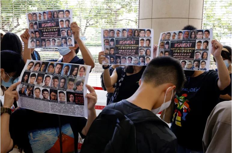 Supporters hold up placards among people queueing up at the West Kowloon Magistrates' Courts.