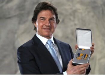 Tom Cruise posing with the Distinguished Public Service Award .