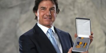 Tom Cruise posing with the Distinguished Public Service Award .