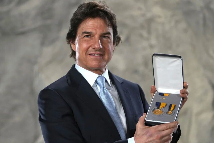 Tom Cruise posing with the Distinguished Public Service Award .