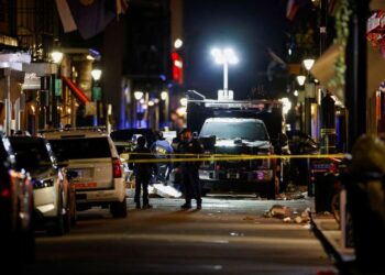 Police officers stand at the scene where a truck drove into a large crowd on Bourbon Street in the French Quarter .