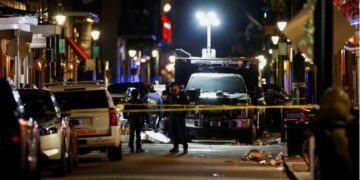 Police officers stand at the scene where a truck drove into a large crowd on Bourbon Street in the French Quarter .